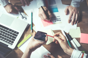 Fototapete - Group of business people working, top view. Loft office and smart casual dress code. Researching new product. Electronic devices and paperwork