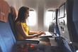 © undrey - Woman using laptop while is sitting in plane near window.
