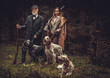© Nejron Photo - Two hunters with dogs and shotguns in a traditional shooting clothing.