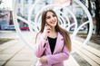 Cheerful woman talking on the phone in the street wearing a pink jacket