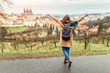 © EdNurg - Woman tourist in a coat with a backpack travels in the city park of Prague, rear view