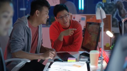  Young game designers looking at computer screen & discussing interface design