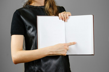 Closeup of girl in black dress holding blank open white book on isolated background. Education concept. Mock up