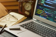 © aleks-p - Laptop with programming code , book , pen and  clock at office desk. Low depth of field.