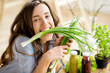 © rh2010 - Portrait of a beautiful woman with fresh onion sitting on the table with healthy food indoors. Vegan meal concept