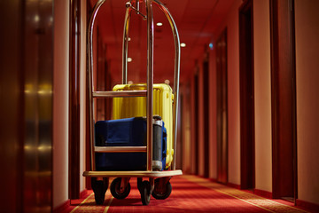 cart of porter with suitcases in aisle of hotel