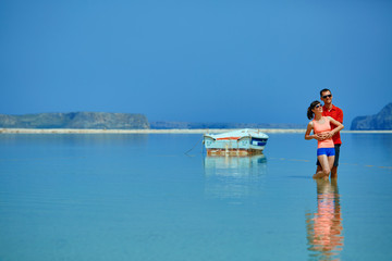 Wall Mural - couple standing in the sea near the boat.