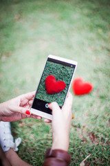 Wall Mural - red heart in smart phone in human hand