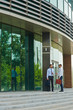 Two young businessmen talking on steps of modern office building with glass fronts