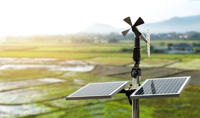 Smart agriculture and smart farm technology concept. Revolving vane anemometer, a meteorological instrument used to measure the wind speed and solar cell system with rice field background.