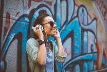 Young Woman Listening To Music Via Headphones On The Street
