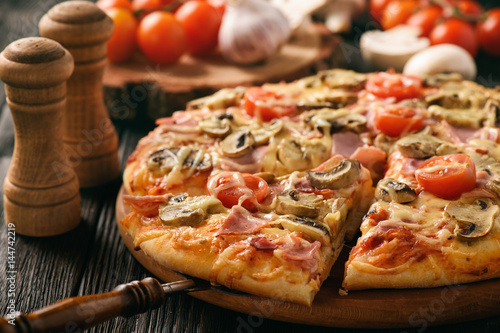 Plakat Domowa pizza z szynką, pieczarkami, pomidorami i serem.
