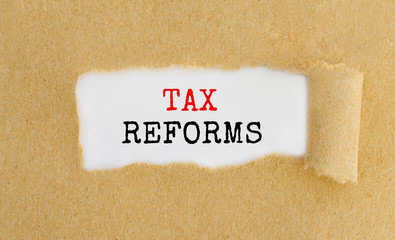 Wall Mural - Text Tax Reforms appearing behind ripped brown paper.