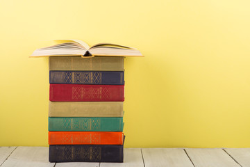 education and wisdom concept - open book on wooden table, color background