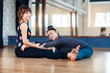 © lena_itzy - Personal trainer helping women in leg stretching workout at gym fitness. Two smiling women warm up before training