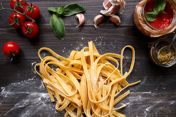 Fresh homemade pasta and vegetables on the dark wooden table top view