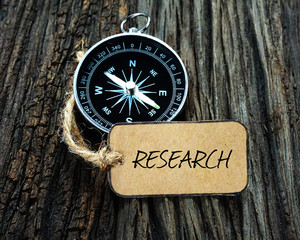 Wall Mural - Compass and paper tag written with RESEARCH on wooden background.