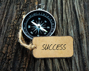 Wall Mural - Compass and paper tag written with SUCCESS on wooden background.