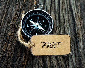 Wall Mural - Compass and paper tag written with TARGET on wooden background.