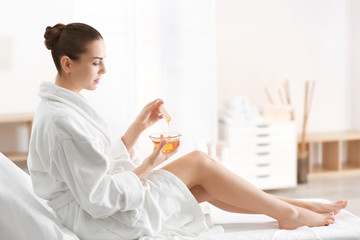 Canvas Print - Woman holding bowl with hot wax in spa center