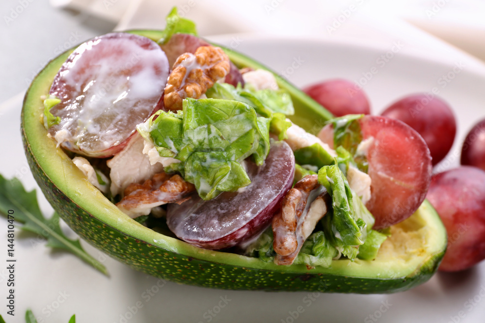 Plate with chicken salad in boat from avocado, closeup