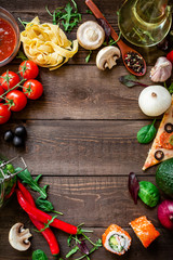 Food frame of vegetables, pizza chips, sushi rolls, mushrooms, tomato, pasta, olives and sauce on wooden background. Flat lay. Top view