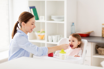 Wall Mural - happy mother feeding baby with puree at home