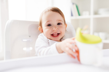 Wall Mural - baby drinking from spout cup in highchair at home