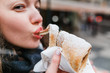 © EdNurg - A woman with an appetite eats a traditional Czech sweet pastry called Trdelnik or Trdlo in Prague street