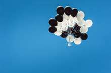 Set Of Black And White Balloons High In The Sky. Cloudless Blue Sky