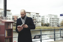 Mid Adult Businessman Reading Book While Standing By River In City