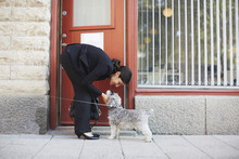Full Length Side View Of Businesswoman Stroking Dog Outside Office