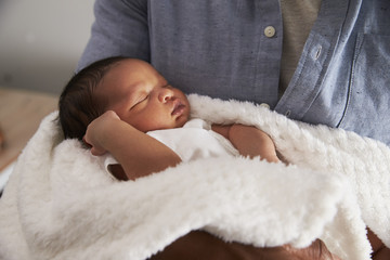 close up of father holding newborn baby son in nursery