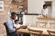 © Monkey Business - Father And Baby Daughter Use Laptop As Mother Prepares Meal