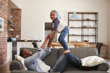 Wall Mural - Father And Son Having Fun Playing On Sofa Together