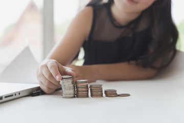 little asian girl put coin to money stack - money saving education concept