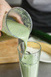 © kkolosov - Crop close up shot of male chef pouring freshly made vegetable smoothie in clean glass.
