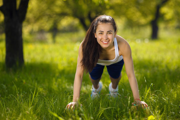 Young girl working out outdoors. Beautiful woman doing pilates, yoga and fitness exercices on nature.