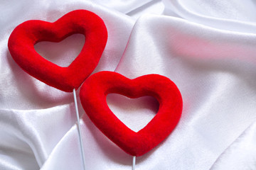 The concept of two lovers hearts lying on the white satin, can be used as a background, texture. Close Up