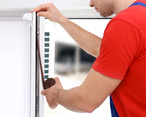 Sticker - Young worker applying rubber strip onto window in office