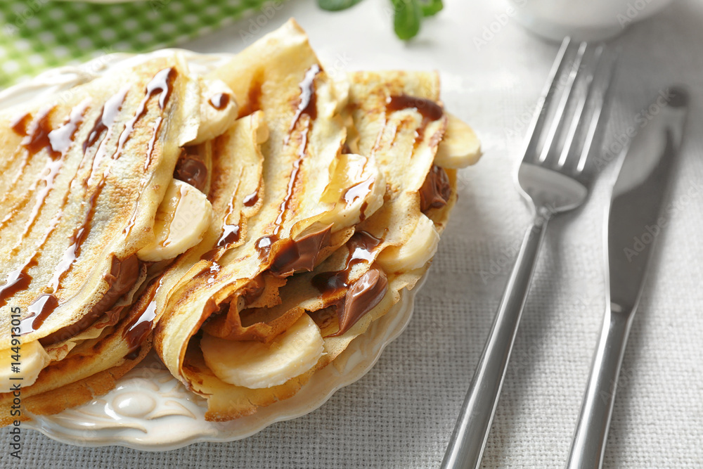 Delicious pancakes with banana and chocolate paste on plate