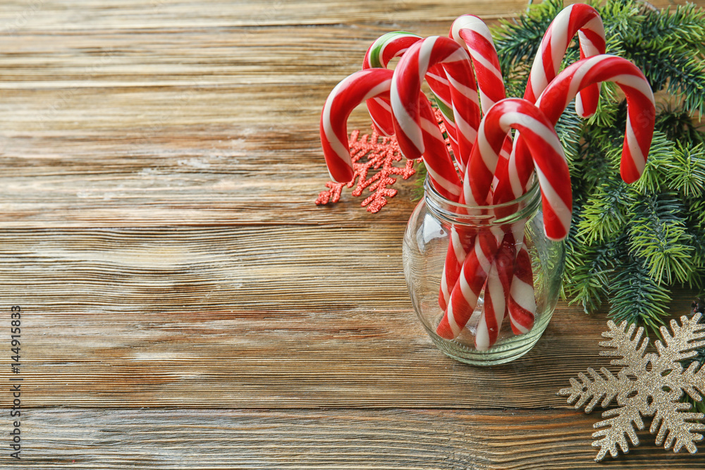 Christmas candy canes in jar and decor on wooden background