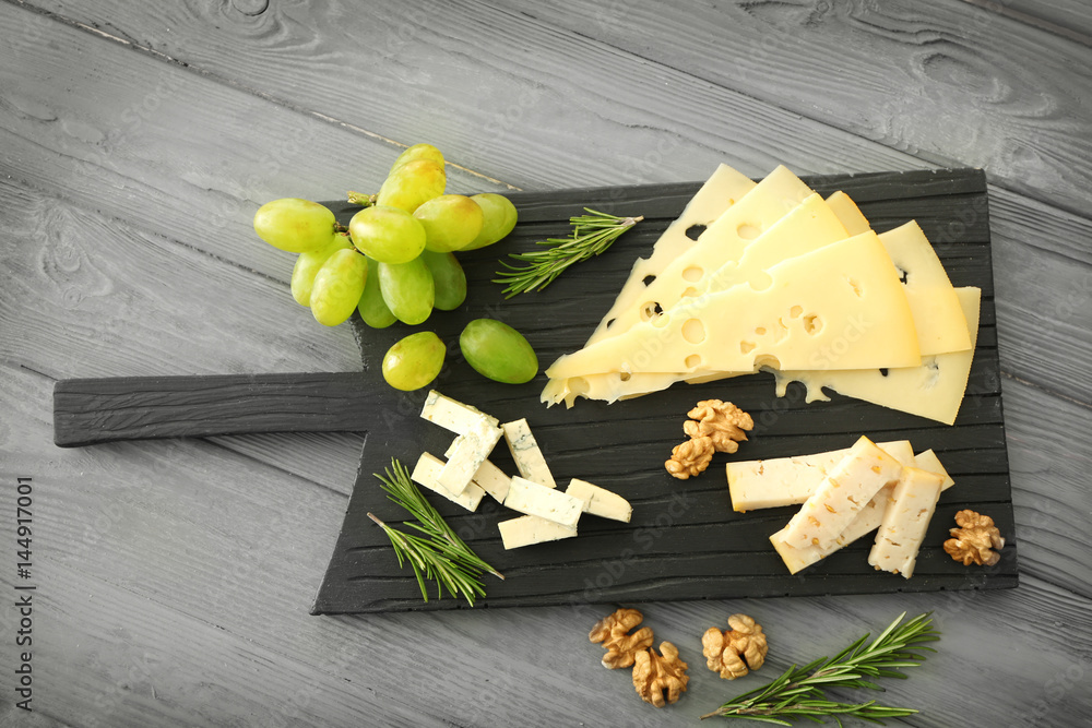 Composition of sliced cheese and walnut on black wooden board