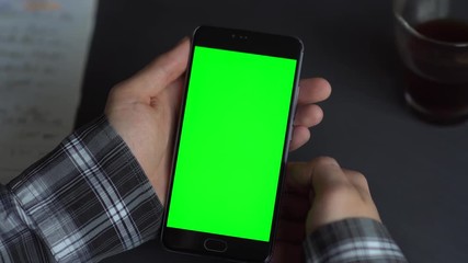 Wall Mural - Swipe up. Man holding a smartphone in the hands of a green screen green screen, hand of man holding mobile smart phone with chroma key green screen on white background, new technology concept