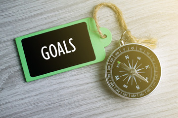 Wall Mural - Compass and wooden tag written with GOALS on grey background.