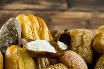 Assortment of baked bread on wooden table background