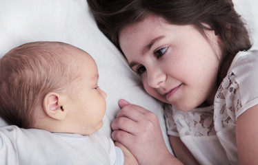 Sister Holding Hand of Newborn Baby Brother