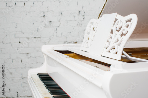 Zdjęcie XXL Biały fortepian w biały pokój z ściana z cegieł