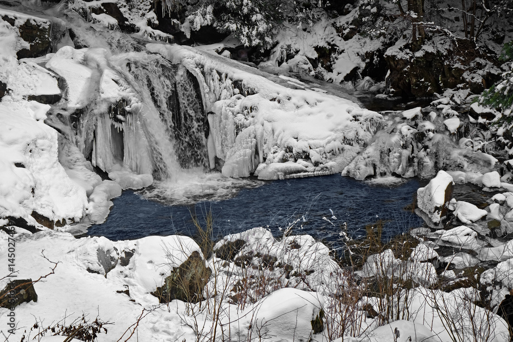 Beautiful landscape with mountain stream and waterfall on winter day