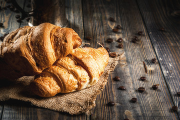 Homemade rustic breakfast in a continental style. On an old wooden table. Croissants and coffee pot with coffee. Copy space